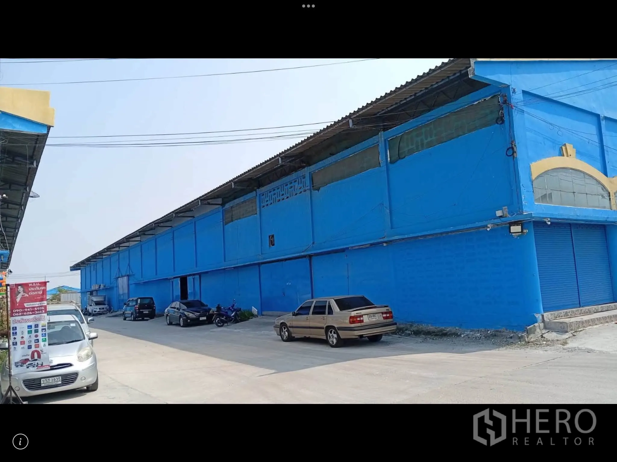 Warehouse for rent in Bang Phli, Samut Prakan - Exterior view of a warehouse row with roller shutter entrances and parking along the access road.