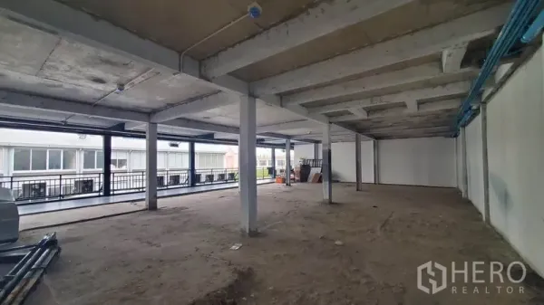 办公空间 出租在Phaya Thai, Bangkok - 开放式毛坯办公室，混凝土柱与裸露天花，一侧为临走廊的整排窗户。