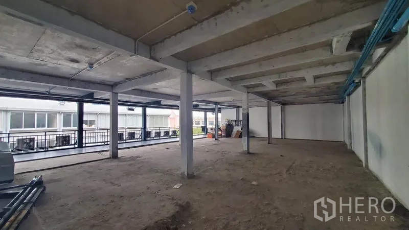 办公空间 出租在Phaya Thai, Bangkok - 开放式毛坯办公室，混凝土柱与裸露天花，一侧为临走廊的整排窗户。