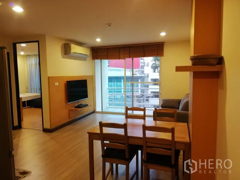 Condominium for rent in Watthana, Bangkok - Dining and living space with wall-mounted TV and wide balcony offering city views near BTS Phrom Phong.