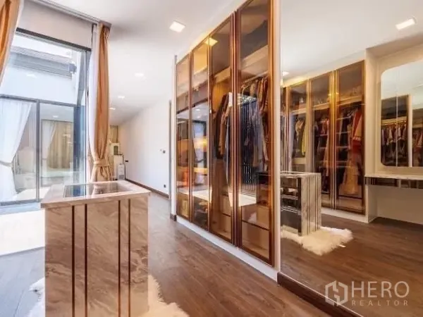 Detached House for sale in Prawet, Bangkok - Spacious walk-in wardrobe with glass-front cabinets, center island, and wood flooring.