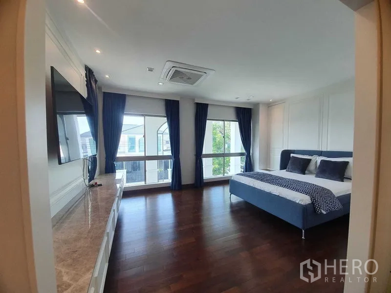 บ้าน ให้เช่าหรือขายในLat Krabang, Bangkok - ห้องนอนใหญ่ พื้นไม้จริง หน้าต่างบานใหญ่ ผ้าม่านสีน้ำเงิน และเตียงคิงไซส์