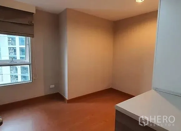 Condominium for rent in Huai Khwang, Bangkok - Bright secondary bedroom with window and wood floors, ready for customization.