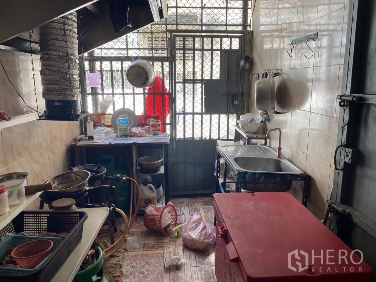 店屋 出租在Khlong Toei, Bangkok - 后部厨房，配不锈钢水槽、燃气炉和金属安全门。