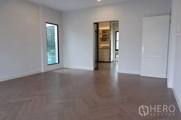 Detached House for sale in Saphan Sung, Bangkok - Empty bedroom with herringbone wood floor and doorway to a walk-in closet.