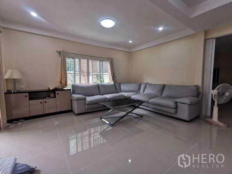 ทาวน์เฮาส์ ให้เช่าในChatuchak, Bangkok - ห้องนั่งเล่นอีกห้องพร้อมโซฟาหนังสีเทาและพื้นกระเบื้องเงา.