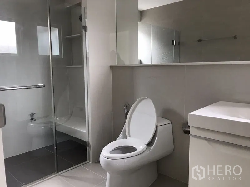 Detached House for rent or sale in Bang Na, Bangkok - Modern bathroom with glass-enclosed shower, toilet and vanity.