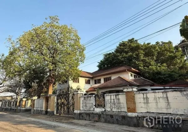 บ้าน ขายในSai Mai, Bangkok - บ้านเดี่ยวสองชั้น สายไหม กรุงเทพฯ หลังคากระเบื้อง รั้วสูง ประตูเหล็กดัดลายหรู และต้นไม้ใหญ่ริมถนนสงบ