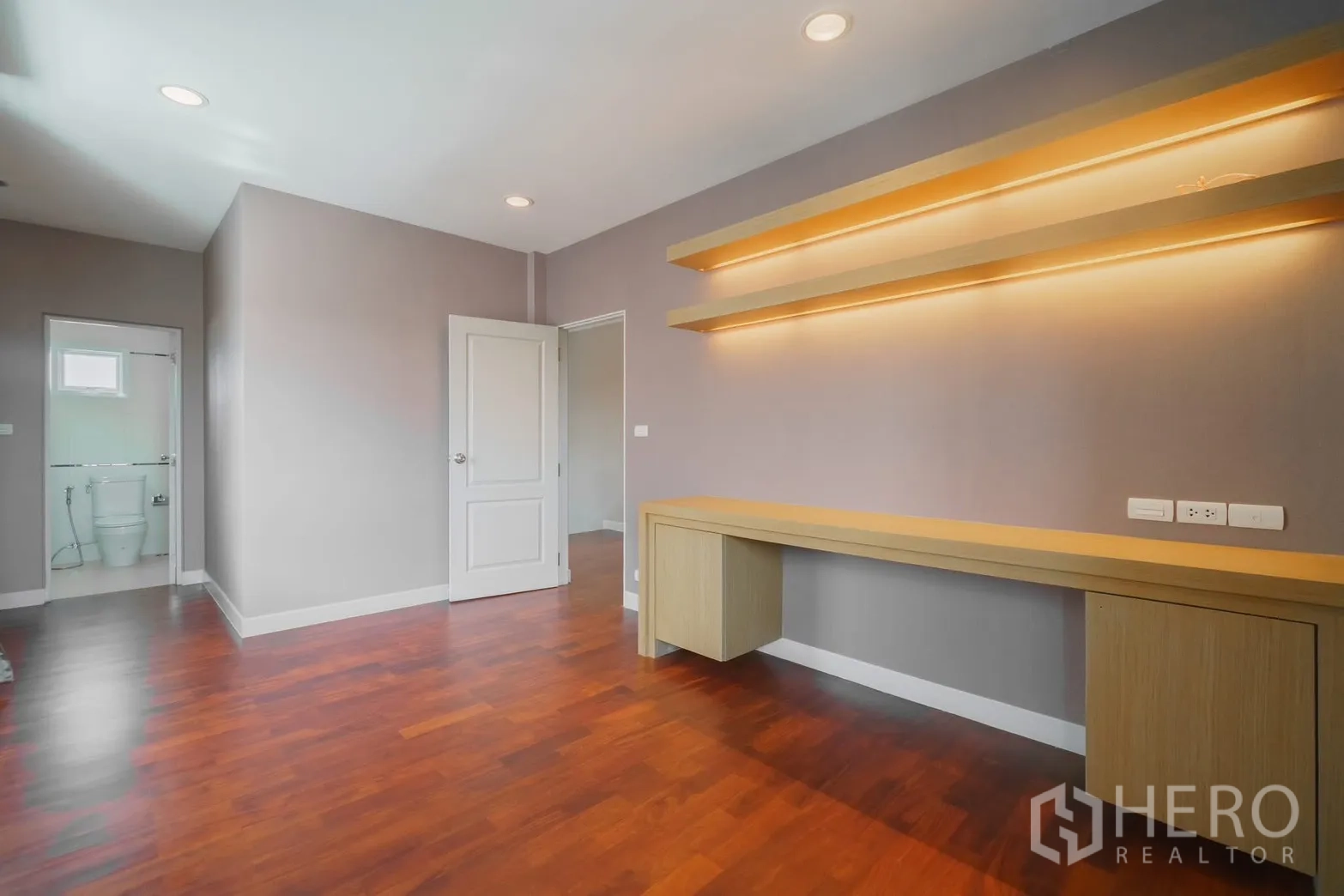 Detached House for rent or sale in Saphan Sung, Bangkok - Bedroom with built-in desk, lit shelves and ensuite bathroom.
