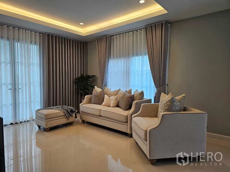 Detached House for rent in Mueang Pathum Thani, Pathum Thani - Cozy living room with sofa set, ottoman and cove lighting