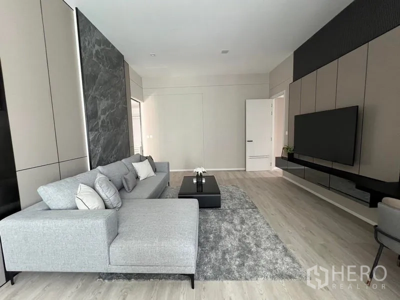 Detached House for rent in Saphan Sung, Bangkok - TV lounge with large sectional sofa, wall-mounted screen and marble accent panel.