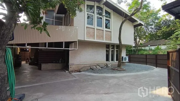 独立式住宅 出租在Phaya Thai, Bangkok - 房屋侧立面，山墙屋顶，围栏庭院，空调外机与宽敞车道。