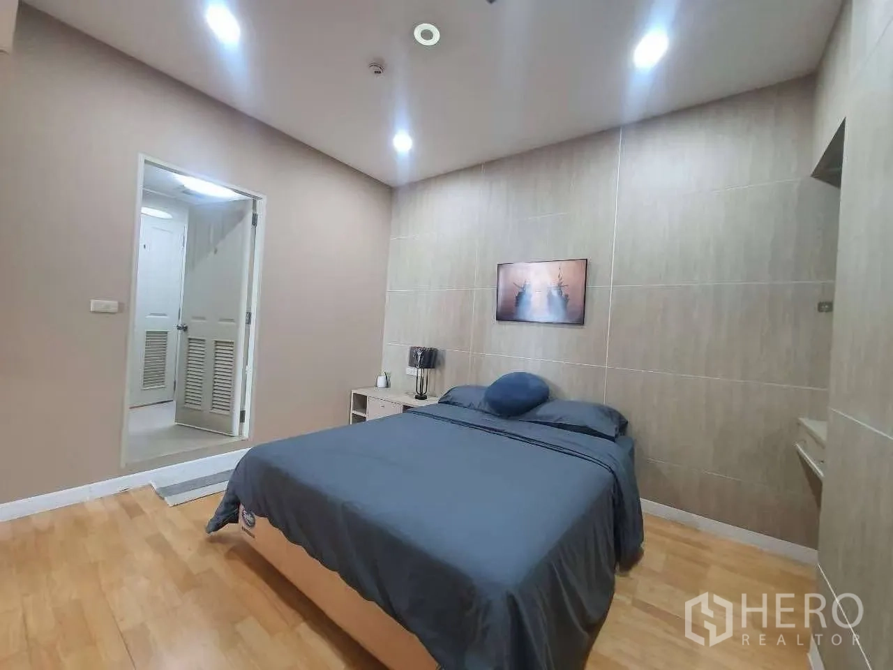 公寓 for rent in Khlong San, Bangkok - 第二卧室设双人床、筒灯与木地板，通往浴室的门可见。