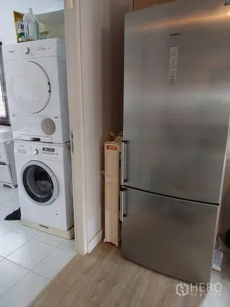 Detached House for sale in Khlong Sam Wa, Bangkok - Laundry nook with stacked washer and dryer beside a stainless-steel refrigerator.