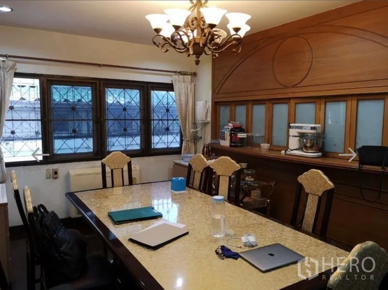 Detached House for sale in Khlong San, Bangkok - Formal dining room with chandelier, built-in cabinetry and a long table.