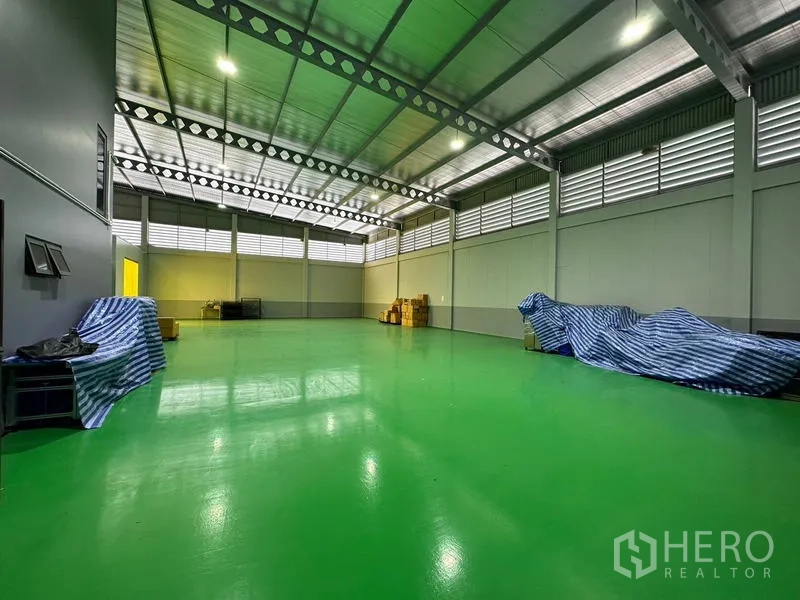 โรงงาน ให้เช่าหรือขายในLam Luk Ka, Pathum Thani - ฮอลล์การผลิตกว้าง พื้นอีพ็อกซี่สีเขียวเงา โครงหลังคาเหล็ก และช่องระบายอากาศ.