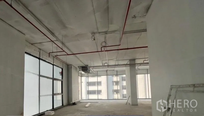 พื้นที่ขายปลีก ให้เช่าในKhlong Toei, Bangkok - พื้นที่ค้าปลีกแบบเชลล์แอนด์คอร์ เพดานสูง ท่อสปริงเกลอร์สีแดง และกระจกเต็มผนัง มองเห็นอาคารเมืองย่านคลองเตย