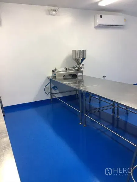 工厂 出租或出售在Pathum Thani - 洁净生产间，配不锈钢工作台、灌装机和蓝色环氧地坪。