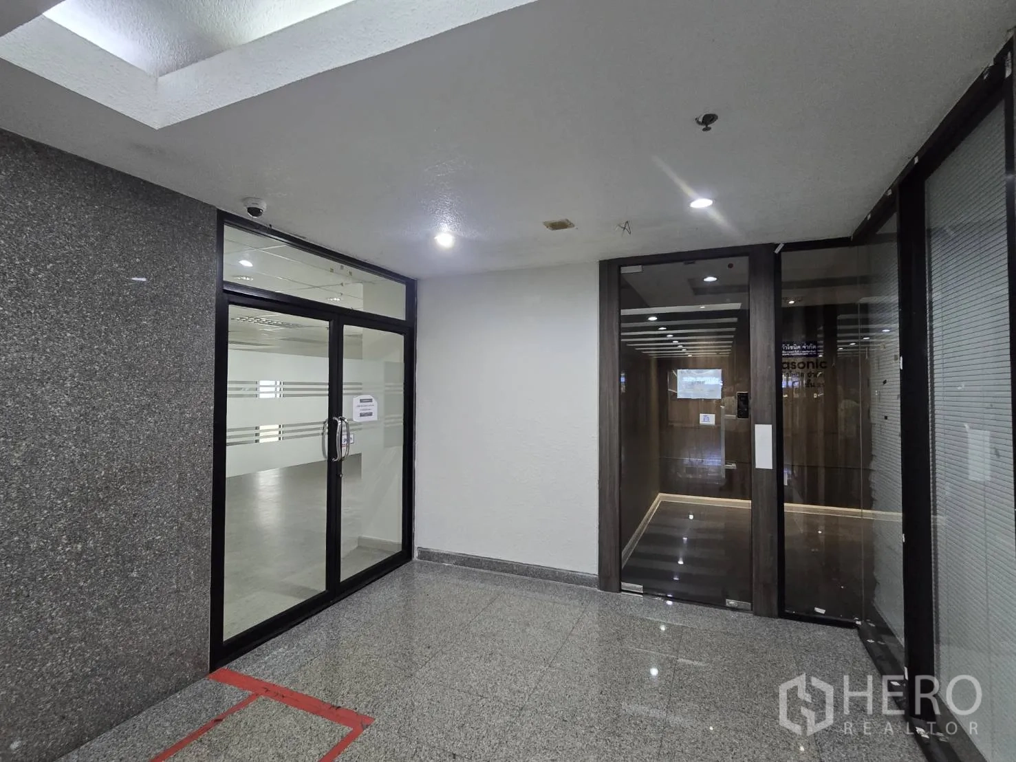 Office Space for rent in Khlong Toei, Bangkok - Building corridor with secure glass doors and polished stone flooring.