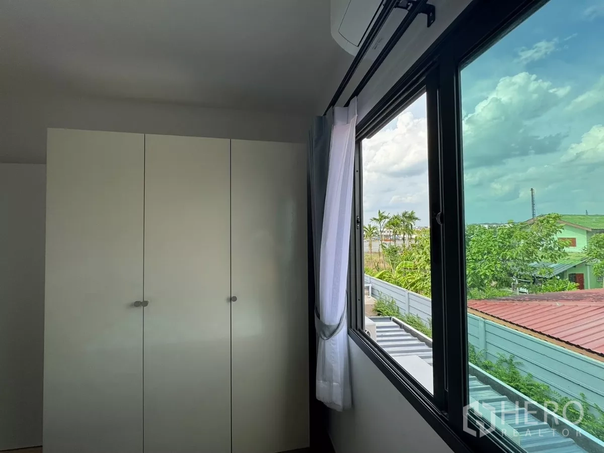 Townhouse for rent in Bang Phli, Samut Prakan - Bedroom window view with wardrobe and rooftops beyond