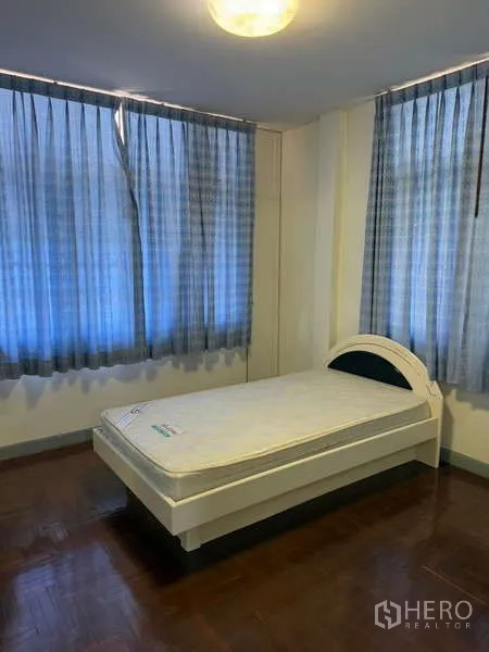 Detached House for rent in Bang Kapi, Bangkok - Secondary bedroom with single bed, blue curtains and wood flooring.