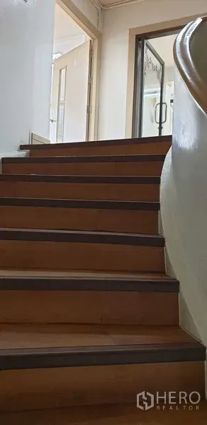 零售空间 出租在Chatuchak, Bangkok - 带弧形扶手的木楼梯，通往带玻璃门的楼上房间。