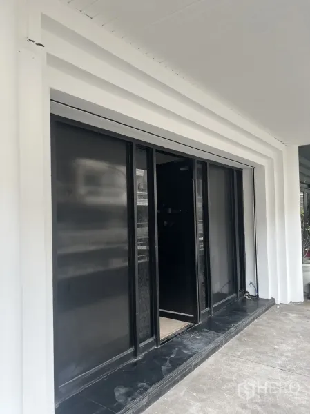 零售空间 出租在Khlong Toei, Bangkok - 一层店面，白色立面与黑色玻璃推拉门。
