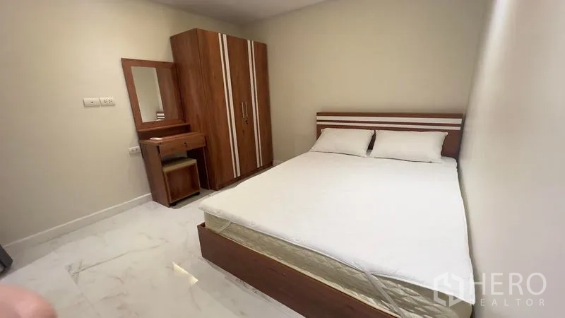 Condominium for rent in Watthana, Bangkok - Second bedroom with double bed, wooden wardrobe and vanity in a Watthana Ekkamai condo.