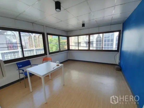 Shophouse for rent in Sathon, Bangkok - Bright corner office room in a Sathon shophouse with large windows and a blue feature wall.