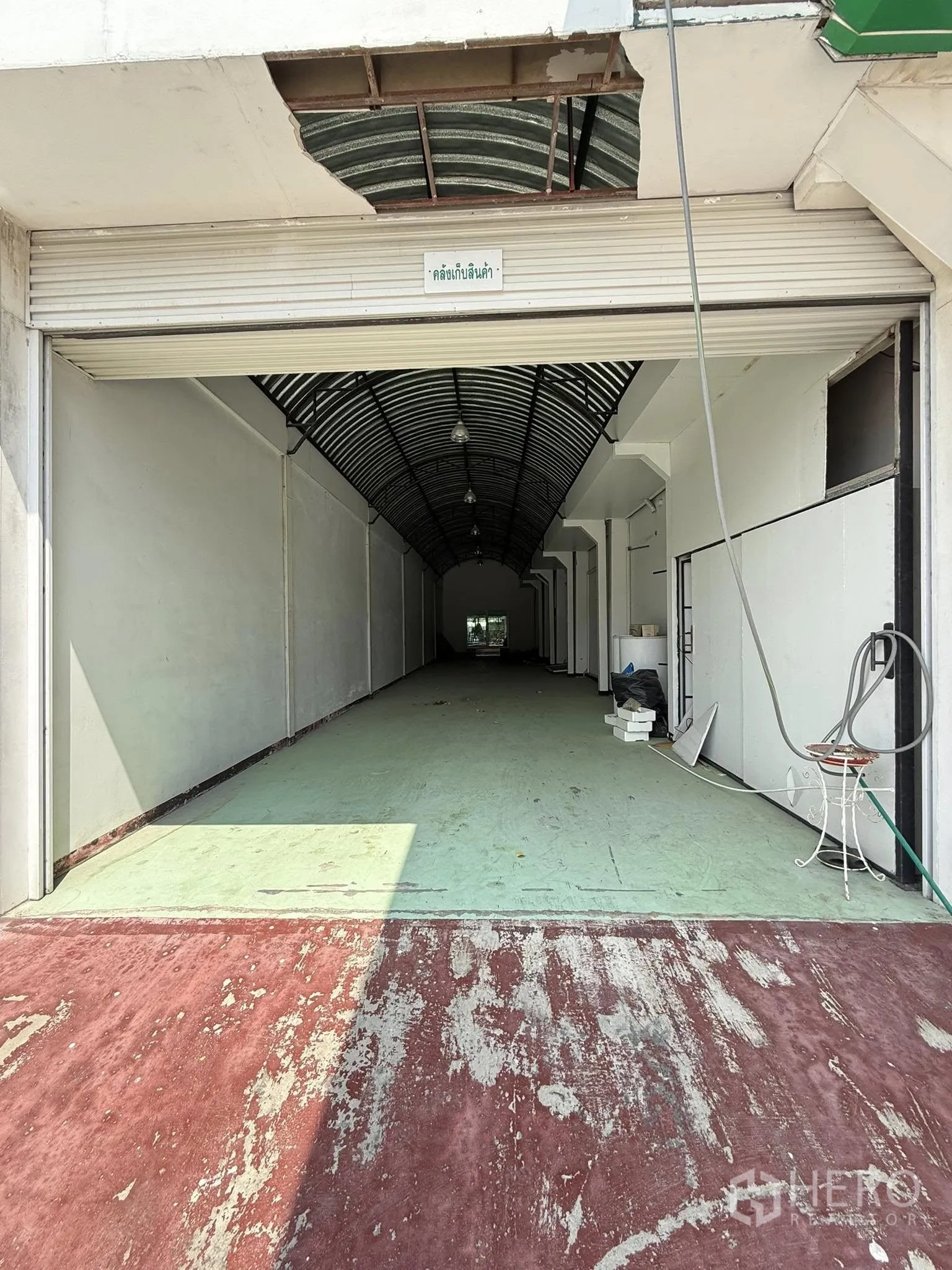 货栈 出租在Mueang Samut Prakan, Samut Prakan - 带卷闸门的狭长仓库通道，拱形金属屋顶。