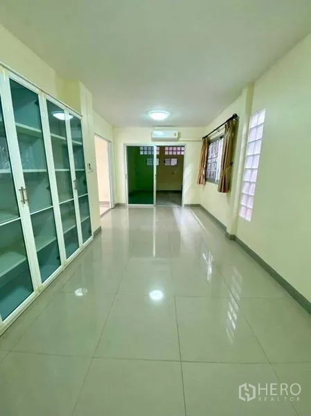 Detached House for sale in Phasi Charoen, Bangkok - Bright corridor with built‑in storage cabinets, glass‑block windows, and sliding doors connecting rooms.