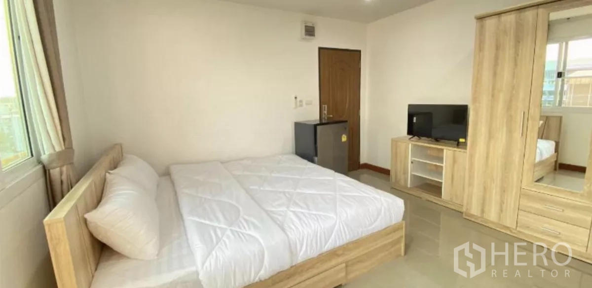 Apartment for sale in Khlong Toei, Bangkok - Furnished bedroom with double bed, wardrobe, TV console and mini fridge beside a window.