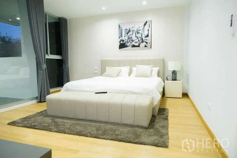 Home Office for rent in Phra Khanong, Bangkok - Serene bedroom with king bed, upholstered bench, rug and soft lighting.