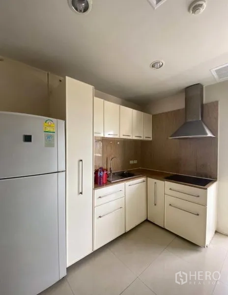 คอนโด ให้เช่าในWatthana, Bangkok - ครัวบิวท์อินขนาดกะทัดรัด ตู้สีขาว ตู้เย็น เตาไฟฟ้า และฮู้ดดูดควันสแตนเลส