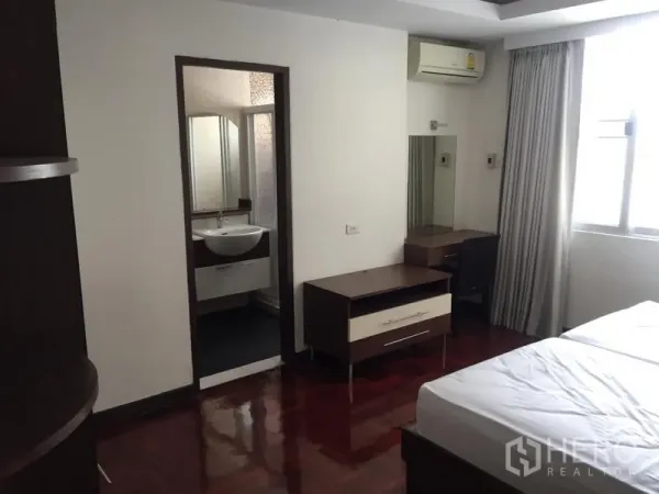 公寓 出租在Khlong Toei, Bangkok - 卧室带木地板、书桌与大窗，连接带洗手盆的套内卫浴