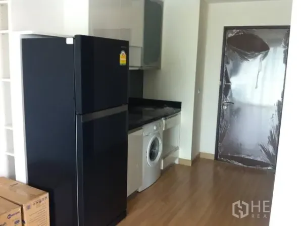 公寓 出租在Watthana, Bangkok - 紧凑厨房配黑色冰箱、洗衣机、石质台面与吊柜，木地板温馨明亮。