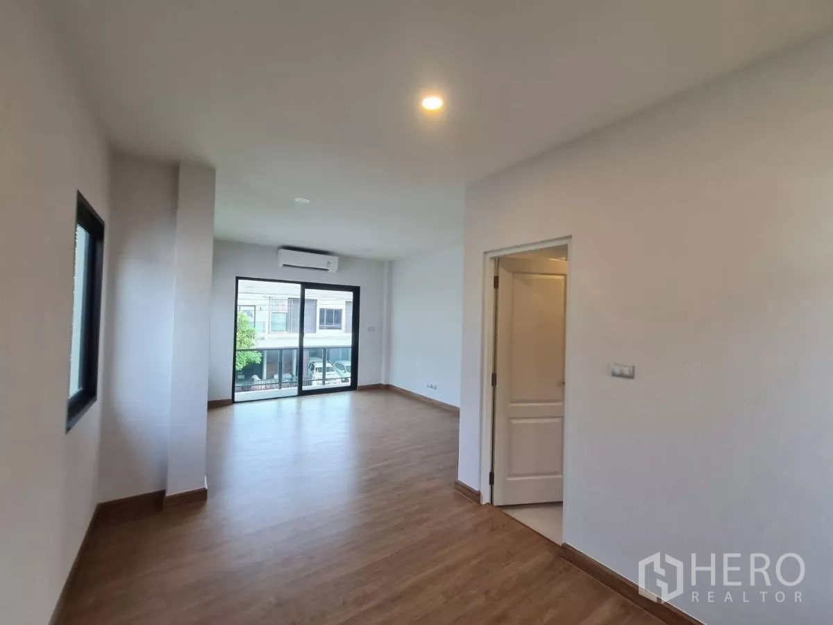 Detached House for sale in Samut Prakan - Upper room with sliding doors to the balcony, air conditioner and adjacent doorway.