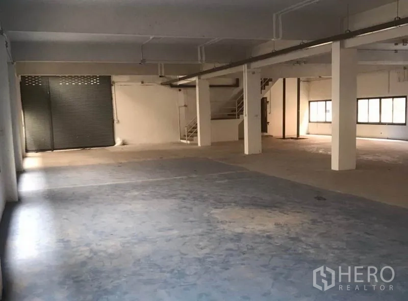工厂 出租在Bang Bua Thong, Nonthaburi - 一层仓储空间，卷闸门、混凝土地面与承重柱