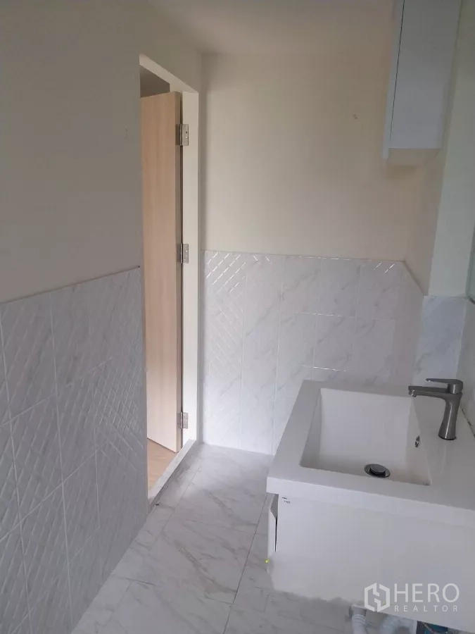 พื้นที่ขายปลีก ให้เช่า - โถงห้องน้ำบุกระเบื้องสีขาวและอ่างล้างหน้า เชื่อมต่อประตูไม้