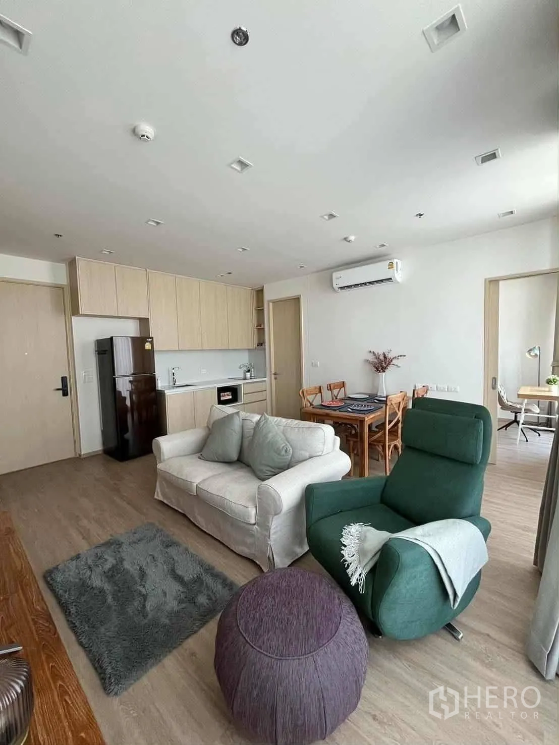 公寓 for rent in Watthana, Bangkok - 客厅连开放式厨房，浅木橱柜、冰箱与舒适座椅。