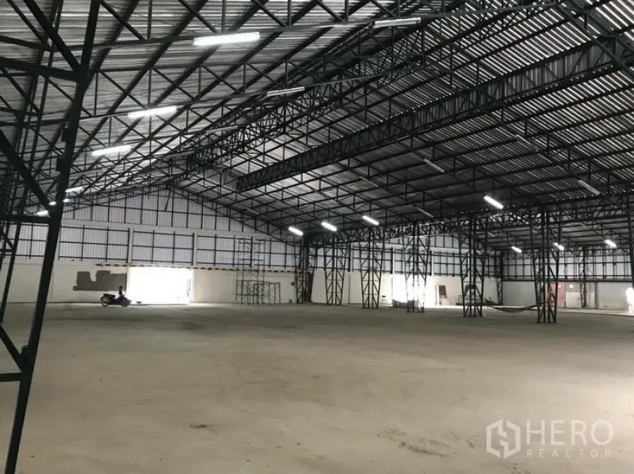 工厂 出租在Min Buri, Bangkok - 宽敞厂房内部，钢架屋顶与混凝土地面。