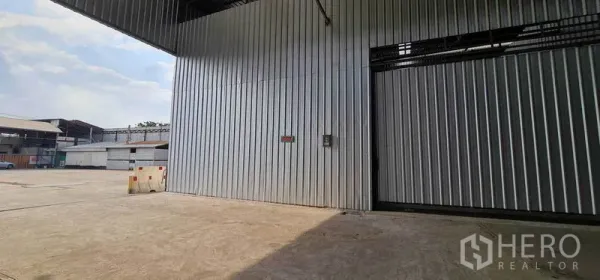 คลังสินค้า ให้เช่าในPak Kret, Nonthaburi - ด้านหน้าโกดังพร้อมลานคอนกรีตกว้างและพื้นที่โหลดสินค้ามีหลังคา