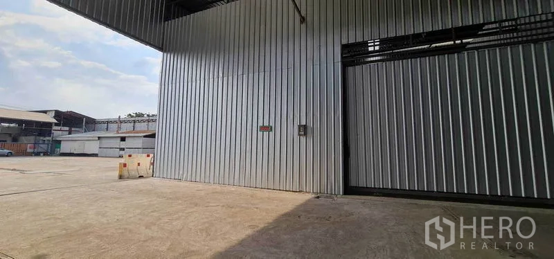 คลังสินค้า ให้เช่าในPak Kret, Nonthaburi - ด้านหน้าโกดังพร้อมลานคอนกรีตกว้างและพื้นที่โหลดสินค้ามีหลังคา
