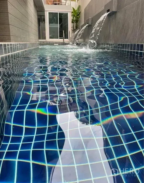 Condominium for rent in Watthana, Bangkok - Condominium swimming pool with blue mosaic tiles and wall water features.