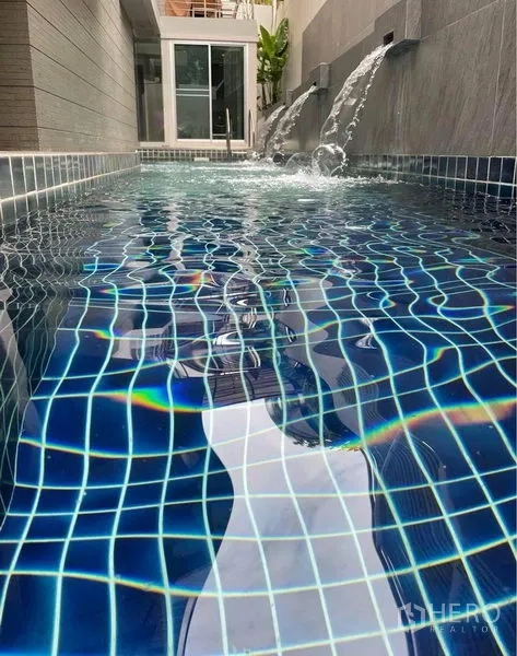 Condominium for rent in Watthana, Bangkok - Condominium swimming pool with blue mosaic tiles and wall water features.
