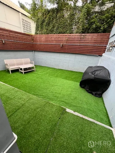 บ้าน ให้เช่าในKhlong Toei, Bangkok - ลานส่วนนอกบ้านปิดรั้ว ปูหญ้าเทียม รั้วไม้ ม้านั่ง และไม้เลื้อย