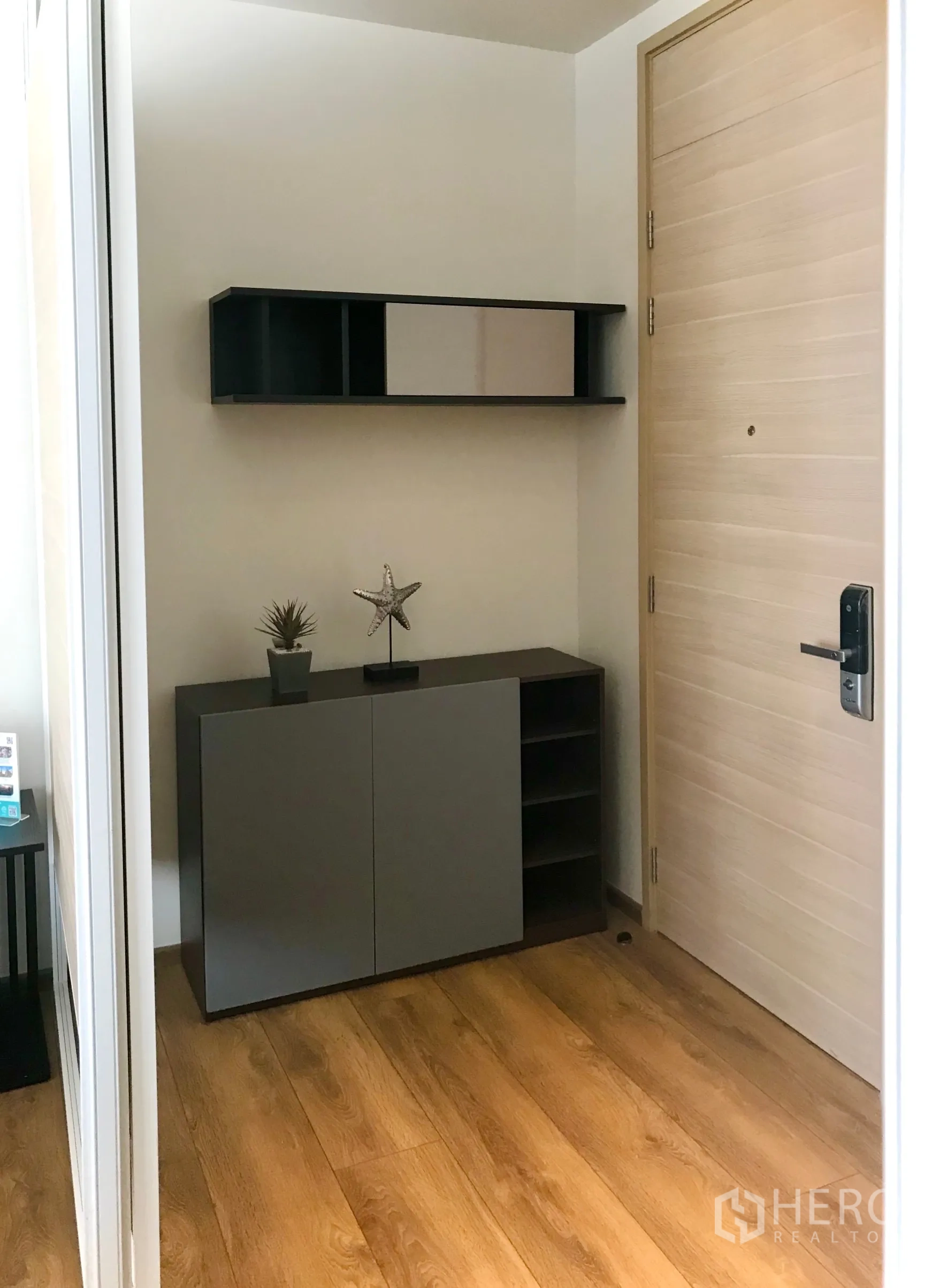 Condominium for sale in Khlong Toei, Bangkok - Entry nook featuring a console cabinet, open wall shelf, and a light wood main door.