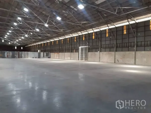 Warehouse for rent in Pak Kret, Nonthaburi - Long-span warehouse showing column-free space, durable concrete flooring and a wide side loading door.