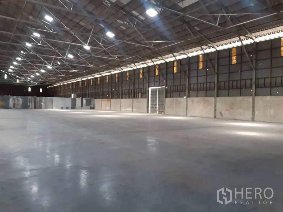 Warehouse for rent in Pak Kret, Nonthaburi - Long-span warehouse showing column-free space, durable concrete flooring and a wide side loading door.