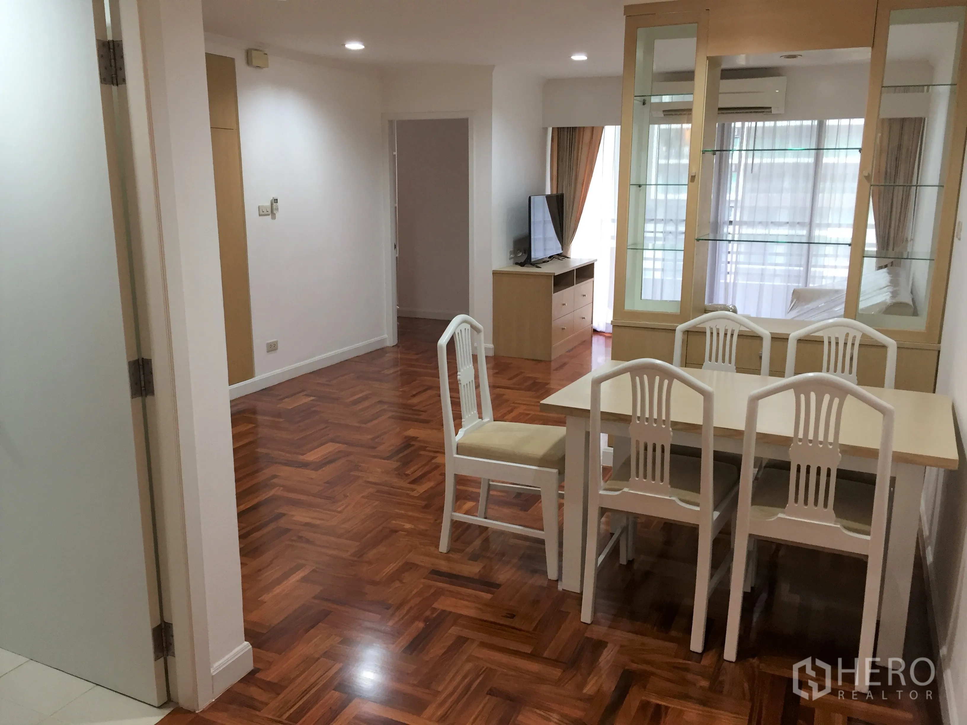 คอนโด ให้เช่าในWatthana, Bangkok - โซนรับประทานอาหารโต๊ะสี่ที่นั่งข้างตู้โชว์กระจก มีตู้วางทีวีและผ้าม่านประตูระเบียง